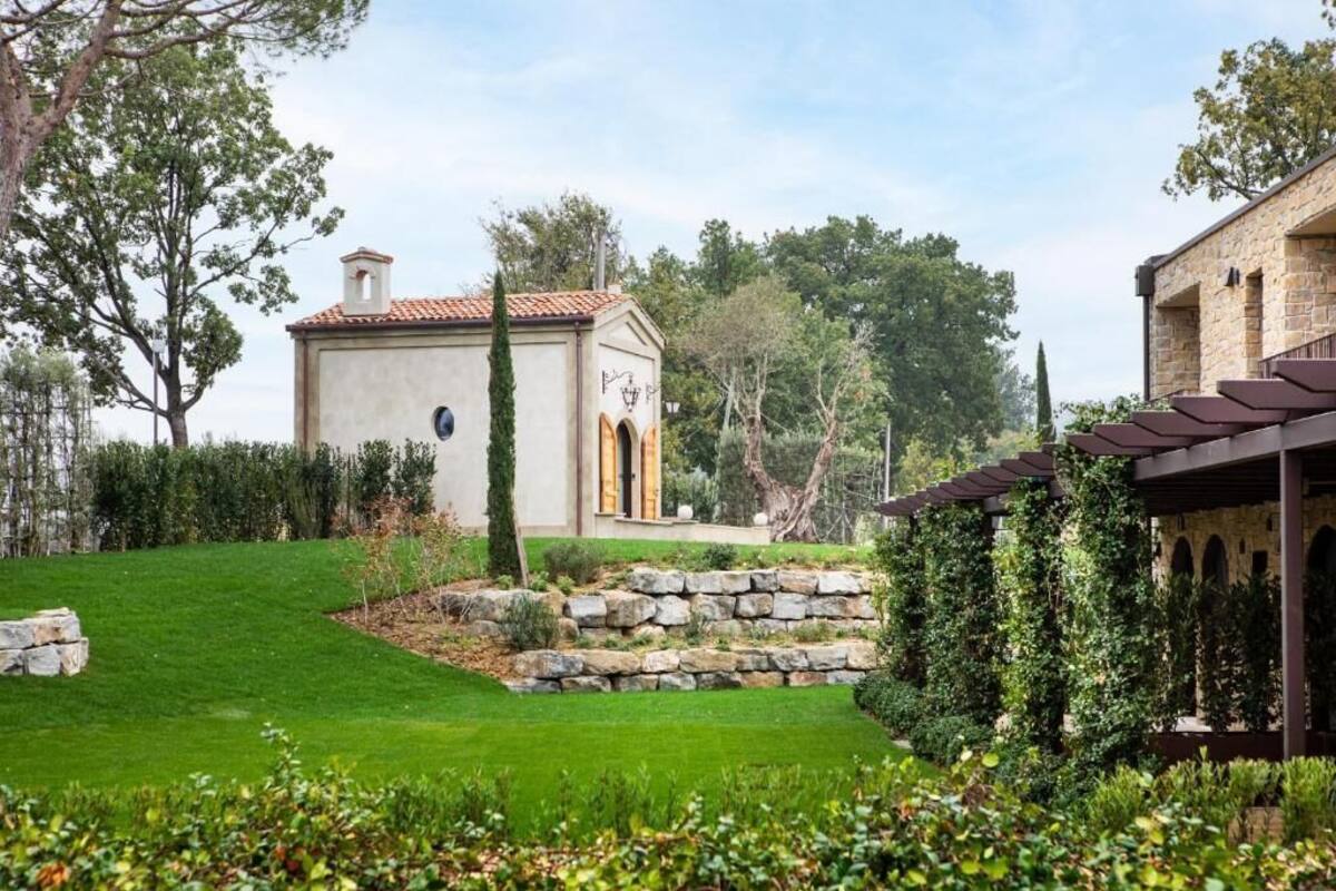 Un jardin bien entretenu, avec un chemin de pierres, un petit bâtiment doté d’un toit en tuiles et une structure en forme de pergola.