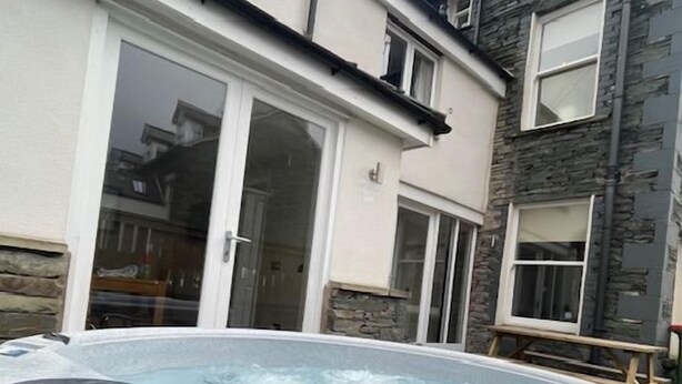 A hot tub in a backyard with a stone wall and a white door.