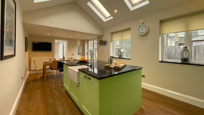 A modern kitchen with a green island, skylights, a dining area, and a view of the outside.