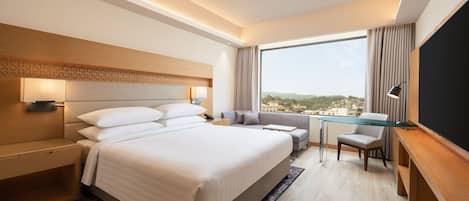 Una habitación de hotel moderna con una cama grande, un escritorio y vistas a la ciudad.