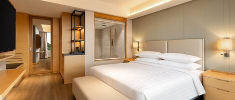 A modern hotel room with a large bed, a bench, a TV, a desk, and a mirror.