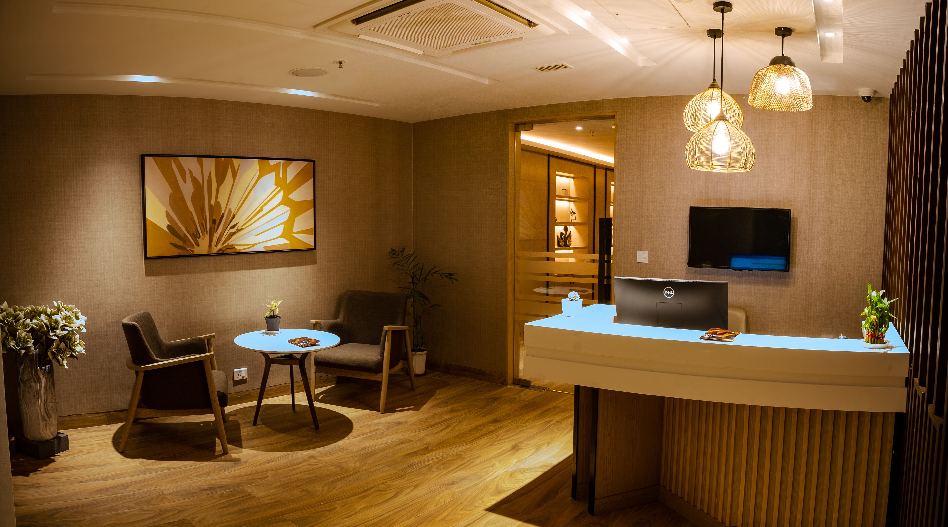 A reception area with a desk, chairs, a laptop, and a television.