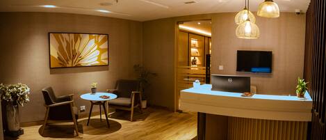 A reception area with a desk, chairs, a laptop, and a television.
