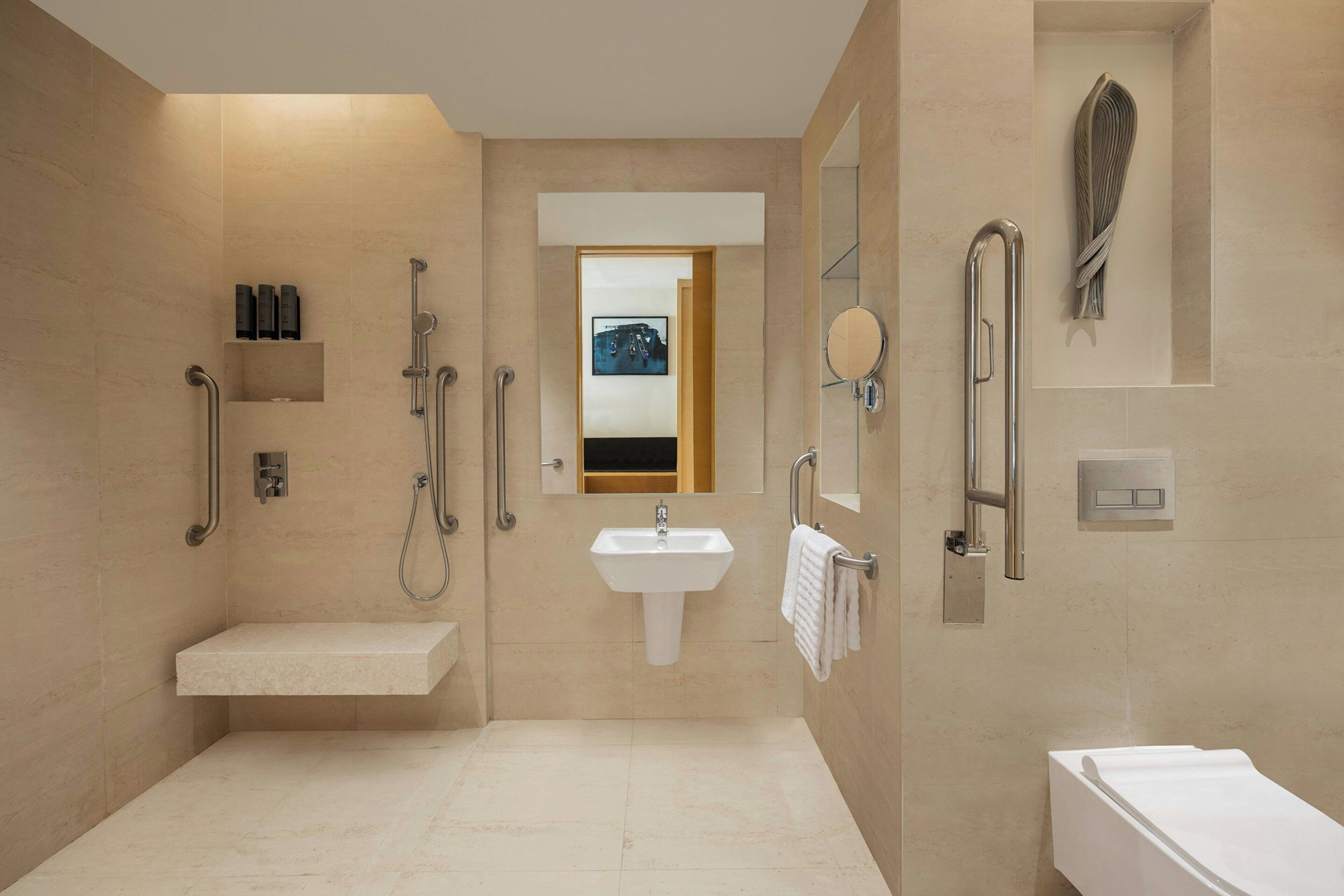 Un baño moderno con lavamanos, espejo, toallero y ducha.
