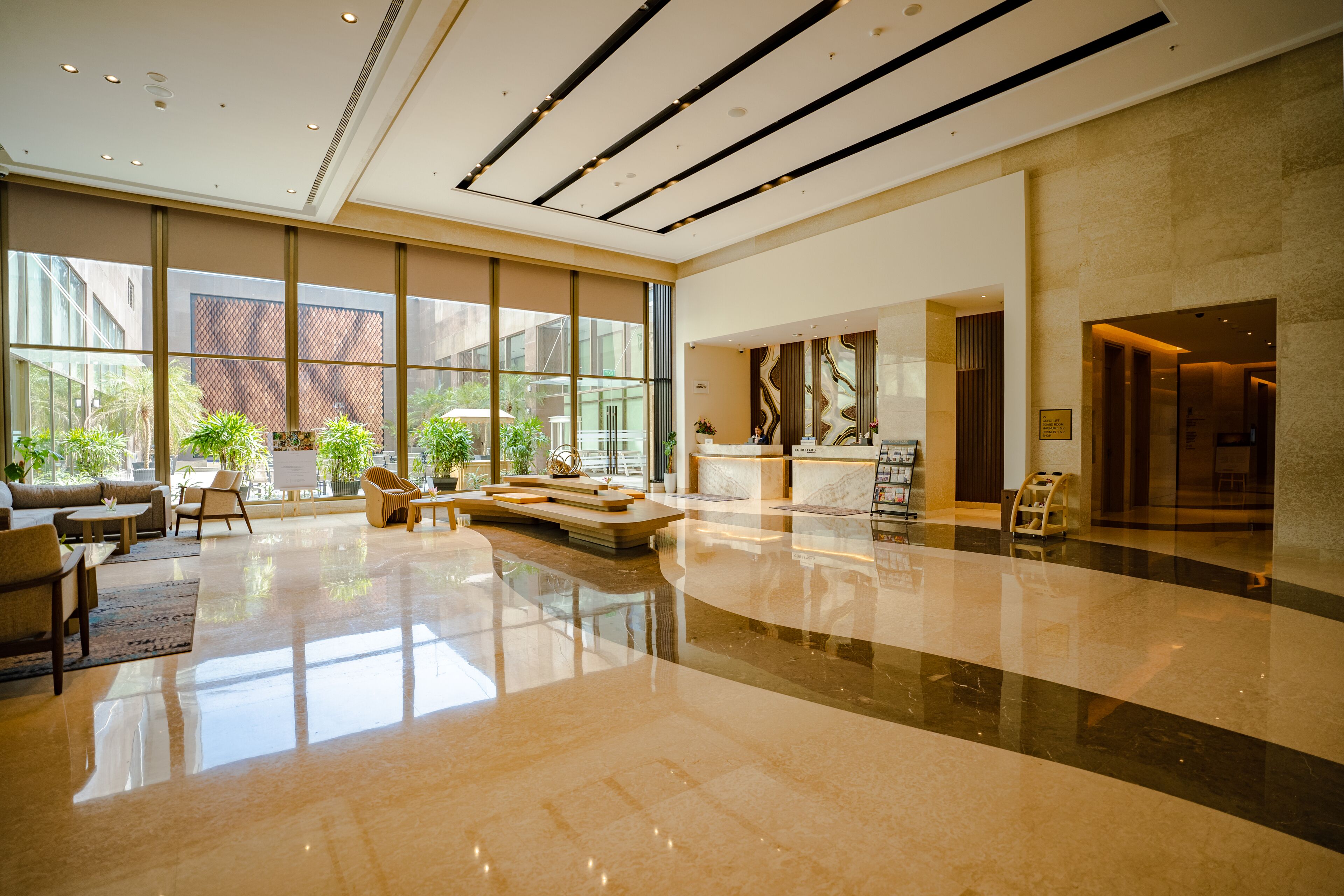 A spacious lobby with a reception desk, seating area, and large windows offering views of the outside.