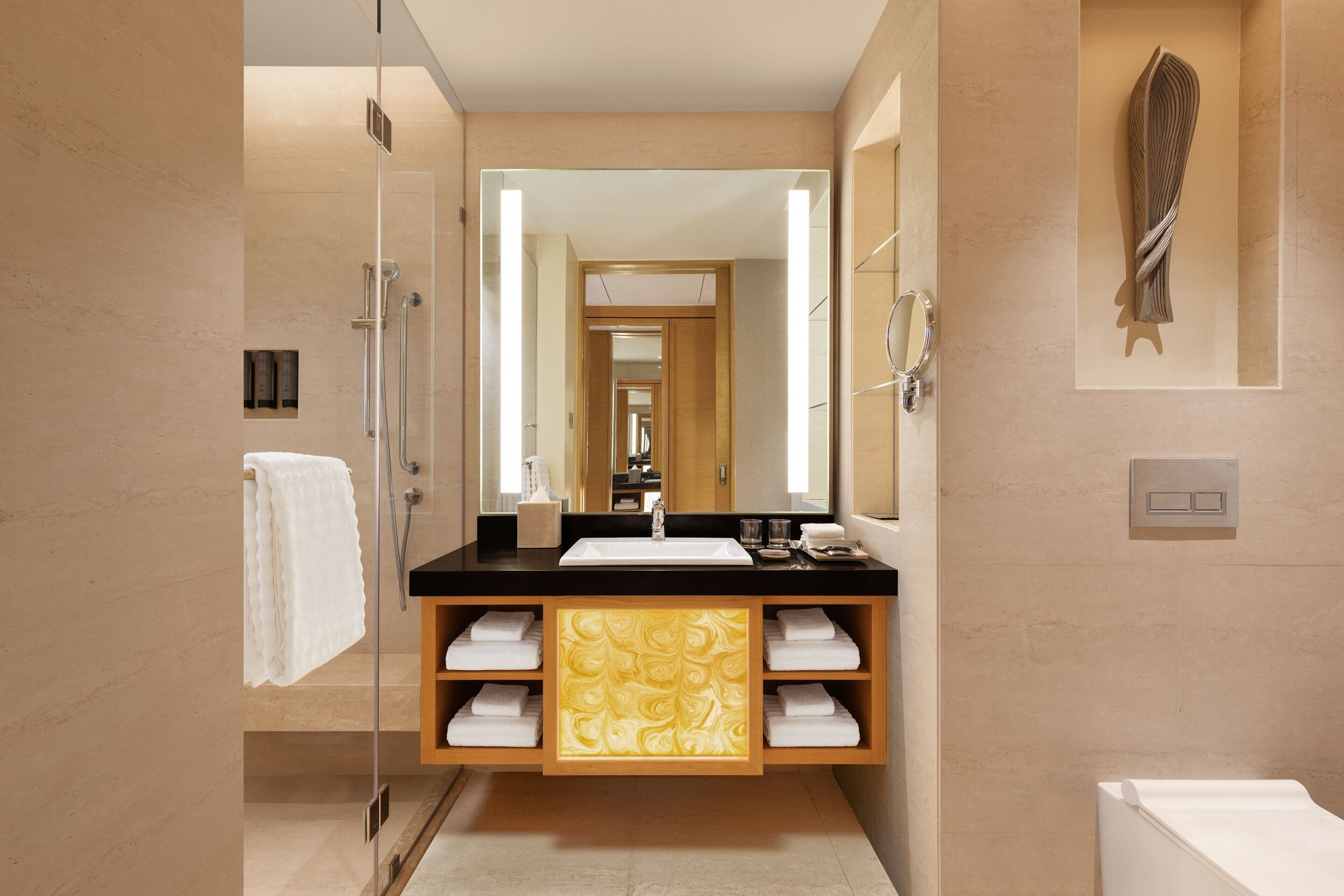 A modern bathroom with a glass shower enclosure, a black countertop sink, and a large mirror.