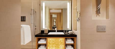 Un baño moderno con cabina de ducha de vidrio, lavabo con encimera negra y un espejo grande.
