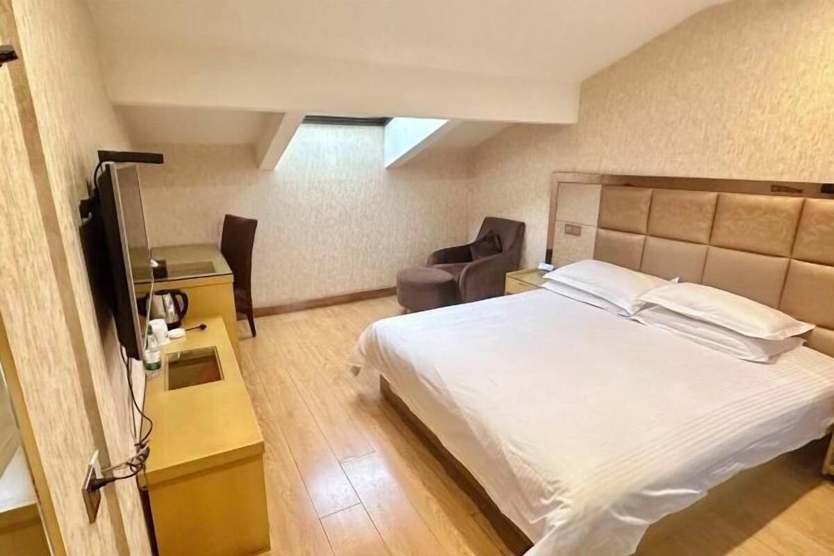 Une chambre d’hôtel avec un lit, une chaise, un bureau avec une lampe et un téléviseur.
