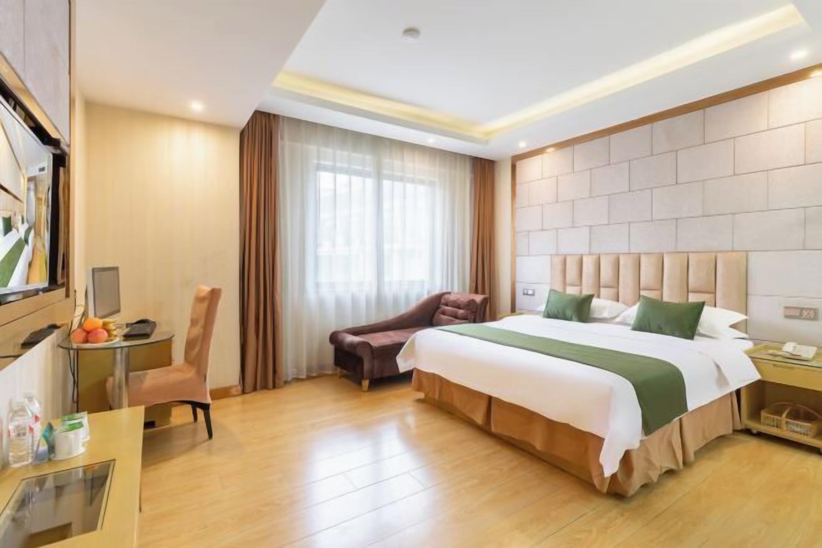Une chambre d’hôtel avec un grand lit, un bureau, une chaise, une télévision et une fenêtre avec des rideaux.