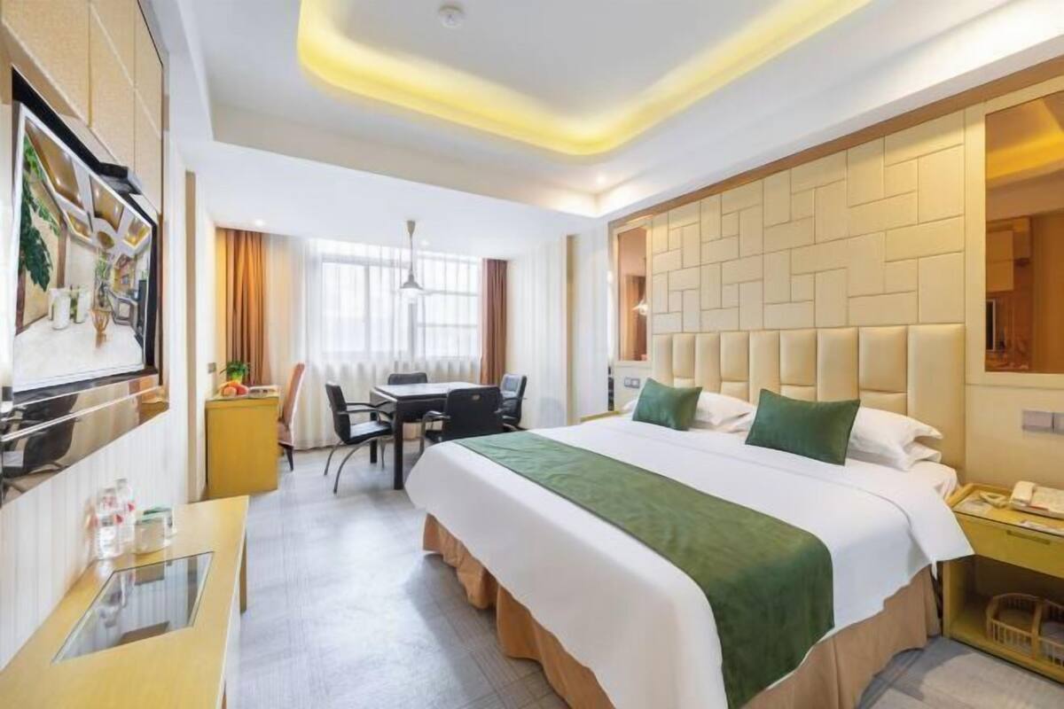 Une chambre d’hôtel avec un grand lit, un bureau, une chaise, une télévision et une salle de bain.