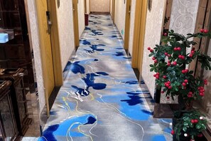 A corridor with a patterned floor, doors on either side, and a potted plant with red berries. - GreenTree Shell Hotel (Yiwu International Business City Changchun Accessories Specialty Street) (Yiwu)
