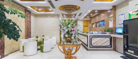 A hotel lobby with a reception desk, seating area, and a decorative centerpiece.