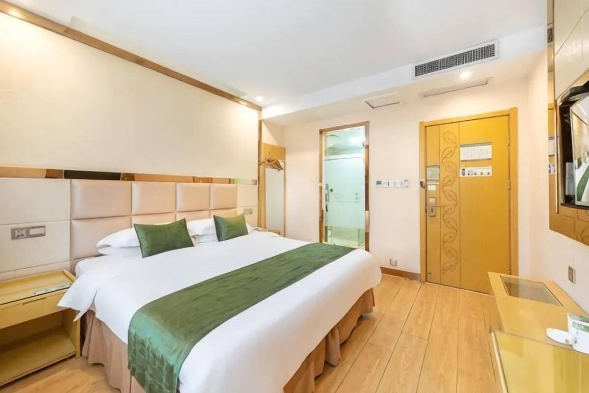 Une chambre d’hôtel avec un lit, un bureau, un miroir et une porte.