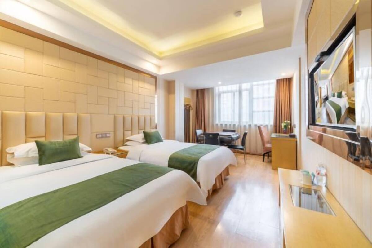 Une chambre d’hôtel avec deux lits, un bureau, une chaise, un miroir et une fenêtre.