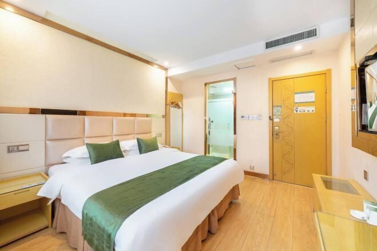Une chambre d’hôtel avec un grand lit, une table de chevet en bois, un bureau et une porte avec une pancarte.