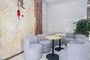 A lobby with round tables and grey upholstered chairs, a decorative wall with a red lantern, and a large green plant. - GreenTree Shell Hotel (Yiwu International Business City Changchun Accessories Specialty Street) (Yiwu)