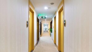A hotel hallway with a carpeted floor, wooden doors, and a ceiling light. - GreenTree Shell Hotel (Yiwu International Business City Changchun Accessories Specialty Street) (Yiwu)