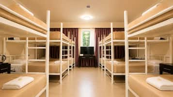 A room with bunk beds, a television, and a window with curtains.
