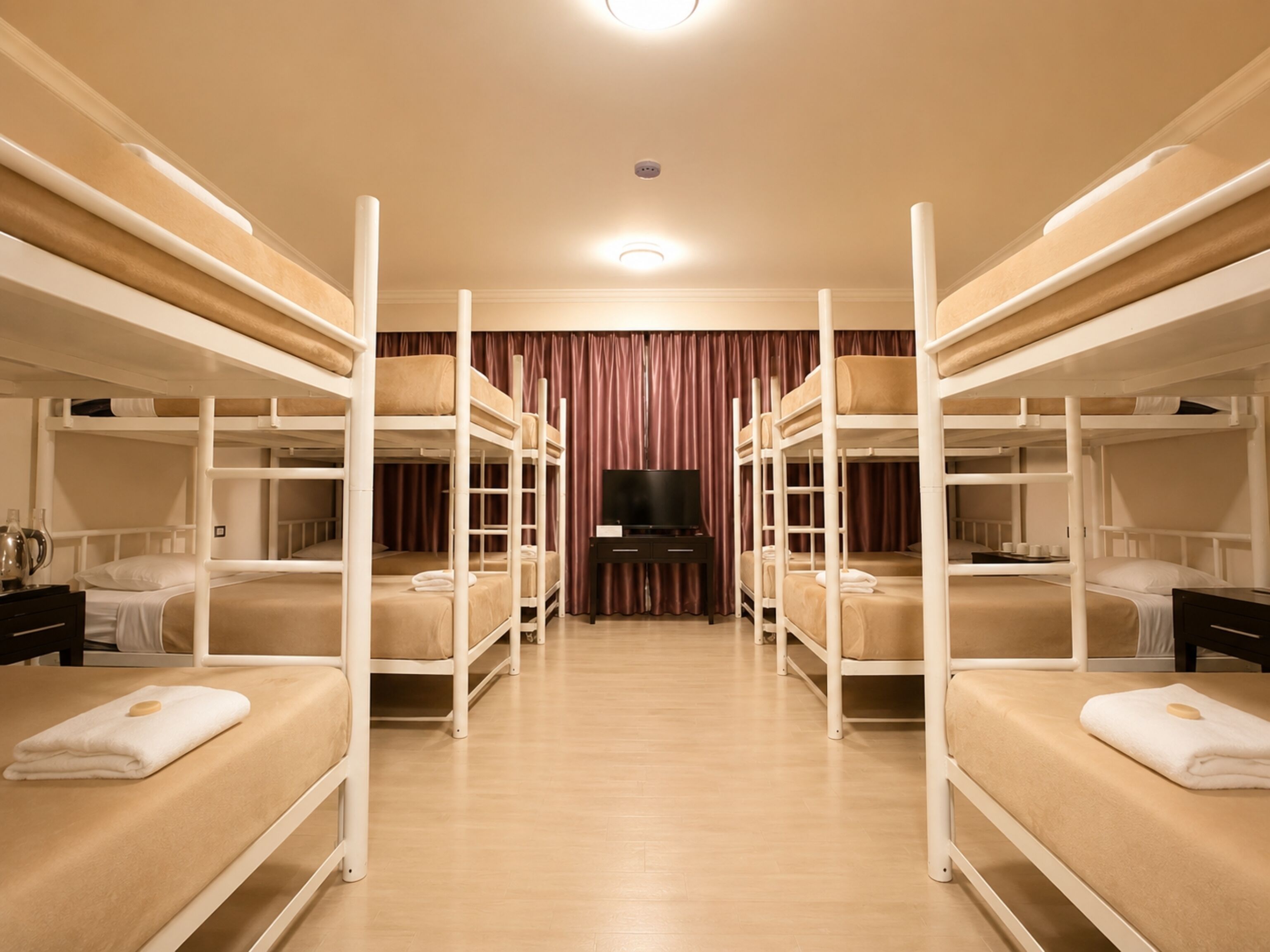A room with bunk beds, a flat-screen TV, and a wooden floor.