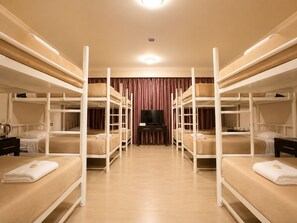 Une chambre avec des lits superposés, un téléviseur à écran plat et un plancher en bois.