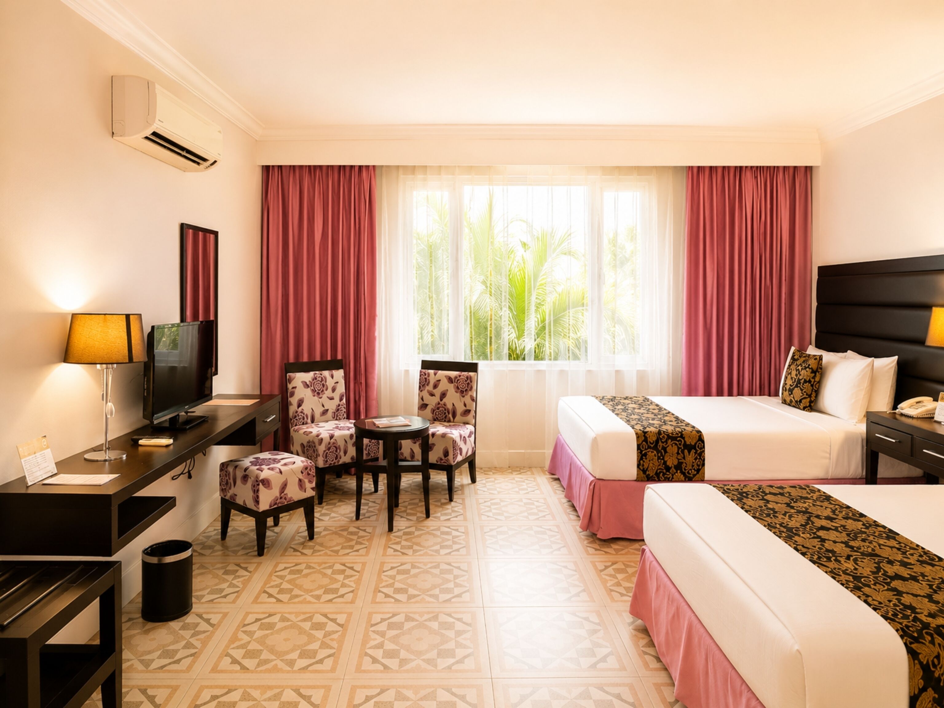 Habitación de hotel con una cama, un escritorio con computadora, una silla, un televisor y una ventana con cortinas.