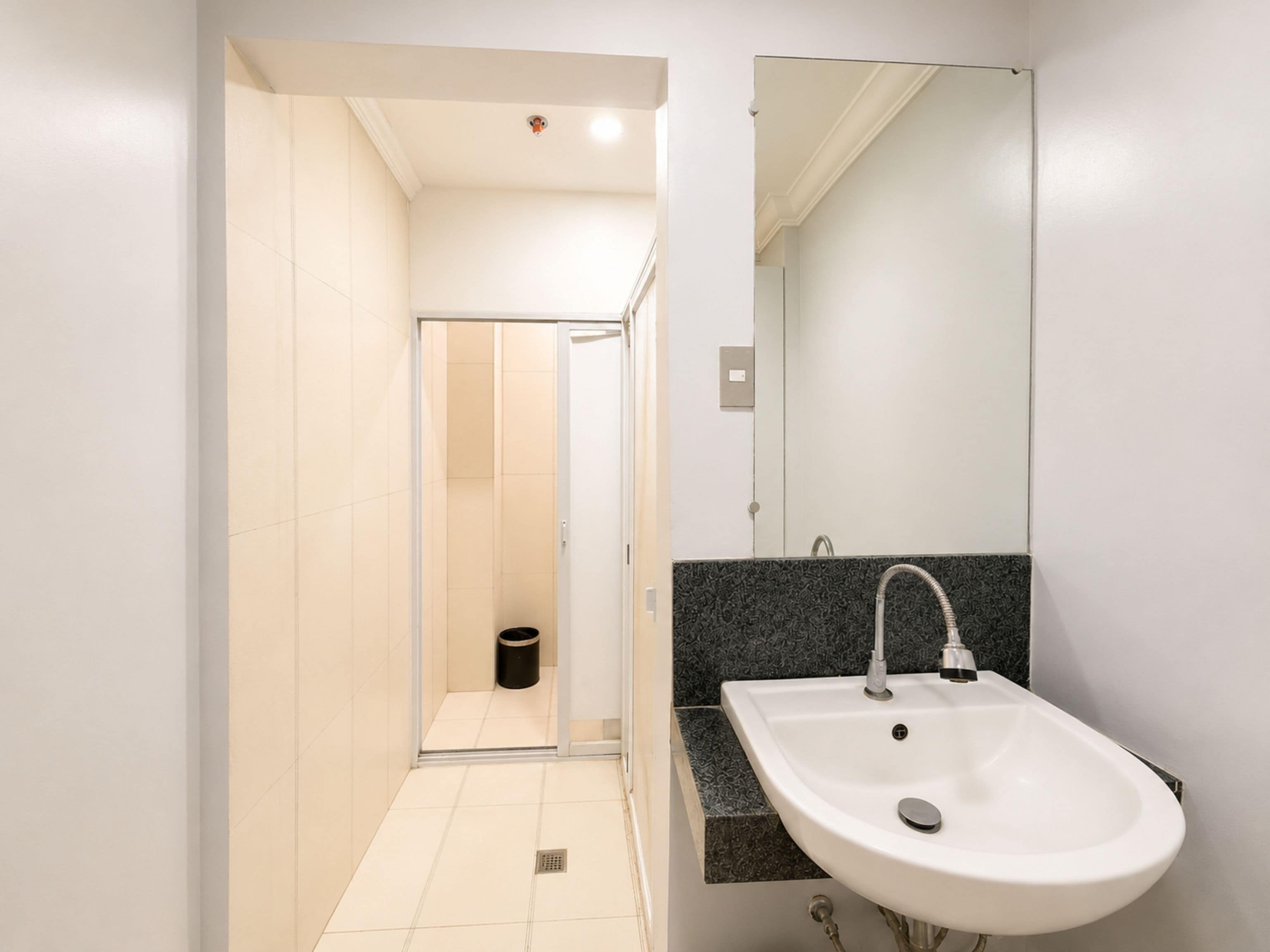 Ein modernes Badezimmer mit einem weißen Waschbecken, einem Spiegel und einer Duschkabine.