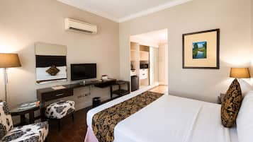 A hotel room with a bed, desk, chair, TV, and wardrobe.