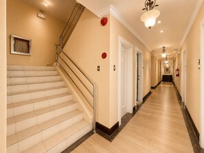 A hotel hallway with a staircase, doors, and a light fixture. - Fiesta Garden Hotel (Bantay)