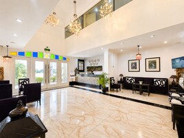 A spacious lobby with a reception desk, seating area, and a large marble floor.