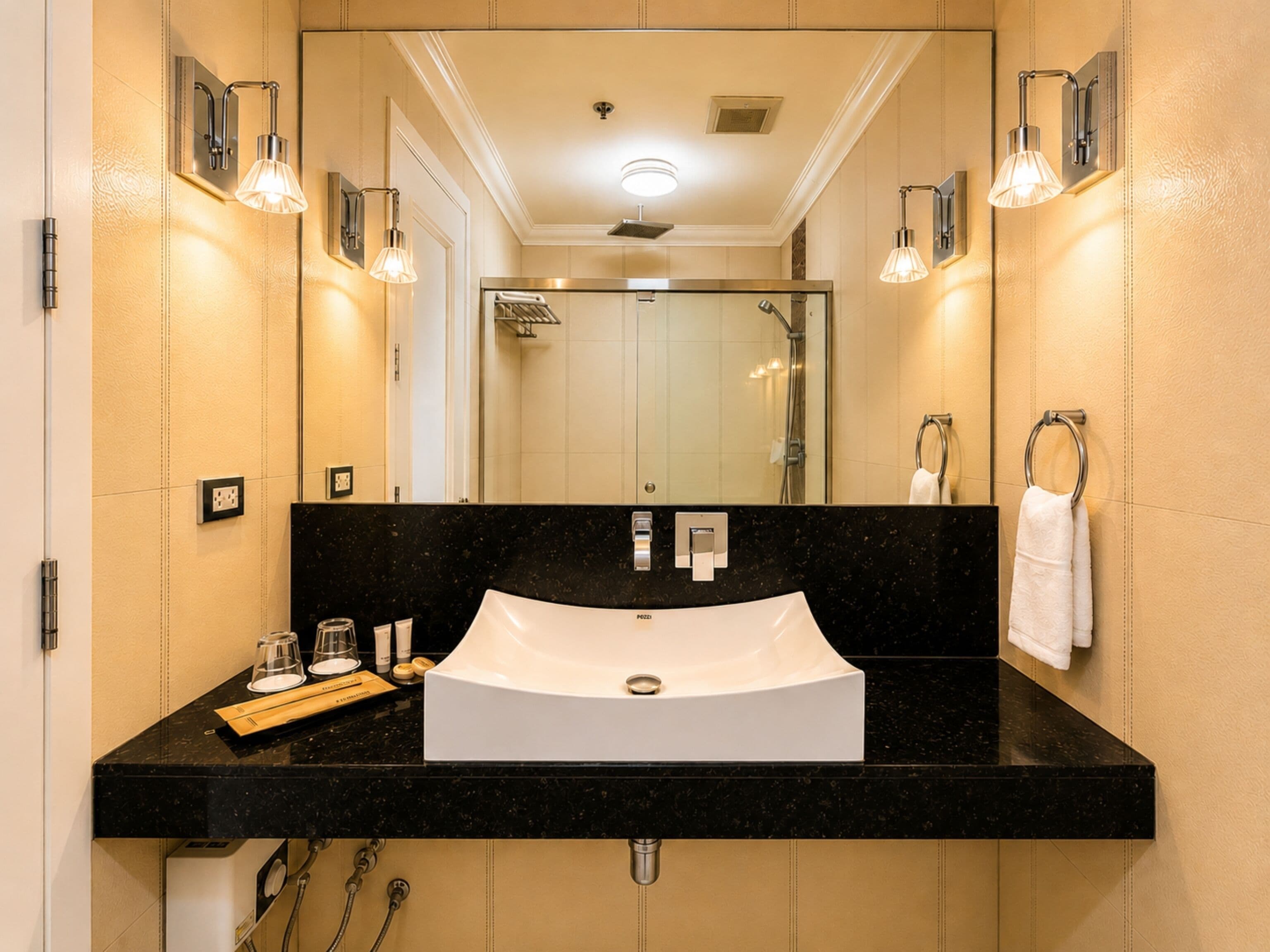 A bathroom with a black countertop, a white sink, and a mirror above it.