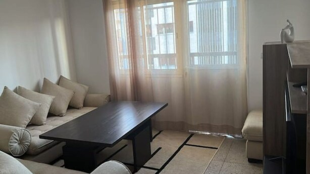A living room with a sofa, a coffee table, a cabinet, and a window with curtains. - Cozy place in the heart of rabat (Rabat)