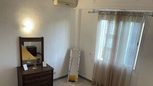 A bedroom with a bed, a dresser, a mirror, a window with curtains, and an air conditioning unit. - Cozy place in the heart of rabat (Rabat)