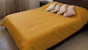 A single bed with a yellow bedspread and three pillows, a wooden headboard, and a nightstand with a lamp. - Cozy place in the heart of rabat (Rabat)