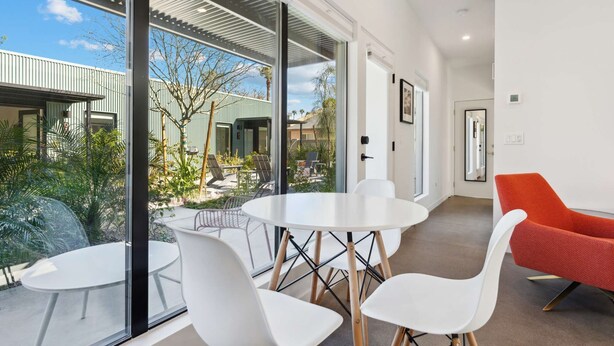 A modern interior with a glass wall overlooking a courtyard, white furniture, and a red chair. - Eco-friendly 2-bedroom Container - 80 Walkscore! (Phoenix)