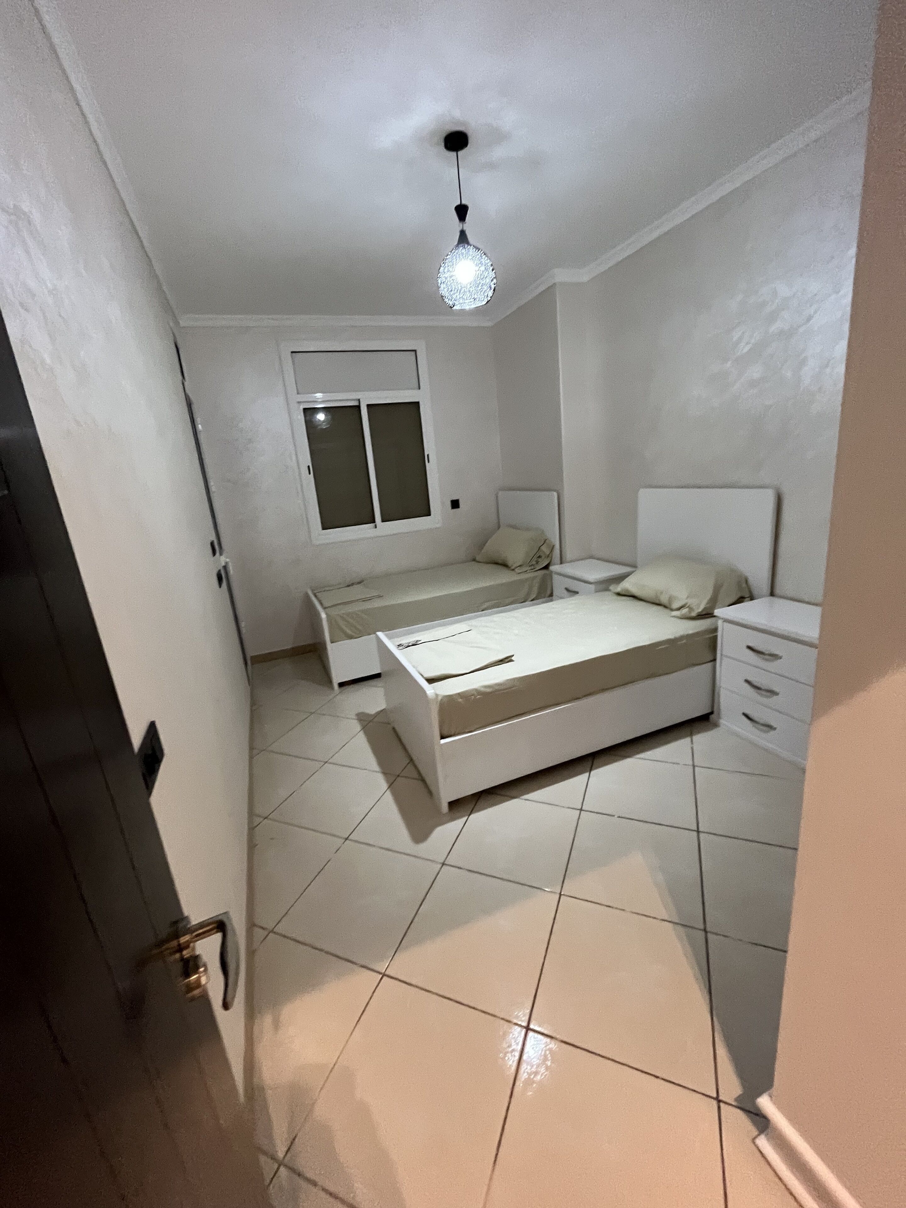 A bedroom with a bed, bedside table, and a window.
