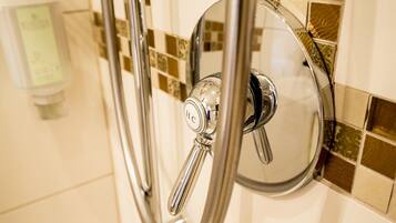 A shower with a chrome faucet and a control panel.