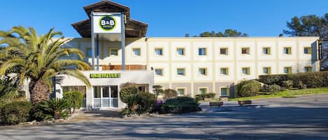Um hotel com uma torre central, várias janelas e um estacionamento.
