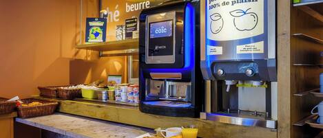 Un espace dédié au café, équipé d’une machine à café numérique, d’un assortiment de viennoiseries et d’un panneau indiquant que le café est préparé avec des ingrédients 100 % français.