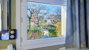 A window with a view of a garden and a building. - B&B HOTEL Cannes Mouans Sartoux (Mouans-Sartoux)