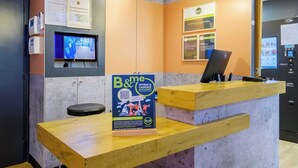 A reception desk with a B&B sign, a computer, and a monitor displaying a room. - B&B HOTEL Cannes Mouans Sartoux (Mouans-Sartoux)