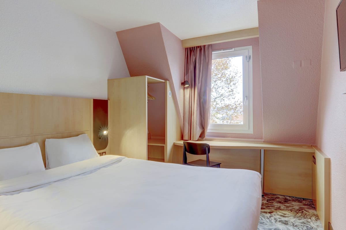 A bedroom with a bed, a desk, a chair, and a wardrobe.