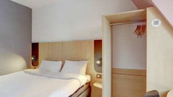 Ein Hotelzimmer mit einem Bett, Nachttischen, einem Holzschrank und einem Spiegel.