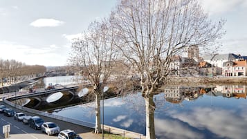 Un río con un puente, coches estacionados y árboles a lo largo de las orillas.