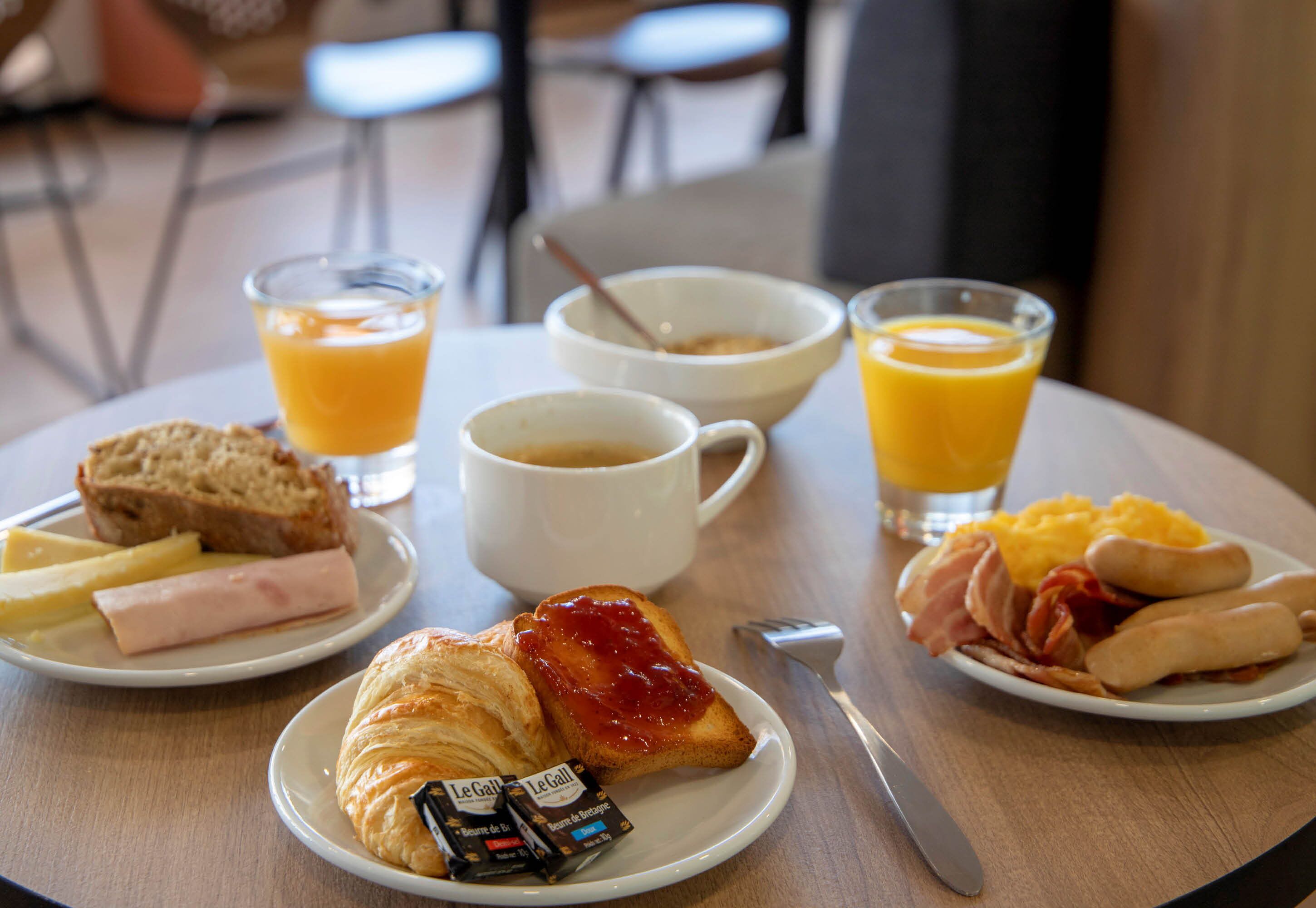 Ein Frühstückstisch mit Croissants, Schinken, Eiern, Toast und Saft.