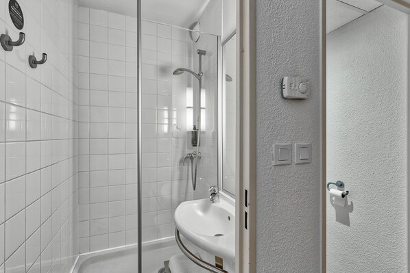 A modern bathroom with a glass shower enclosure, a white sink, and a mirror. - B&B HOTEL Montluçon Saint-Victor (Saint-Victor)