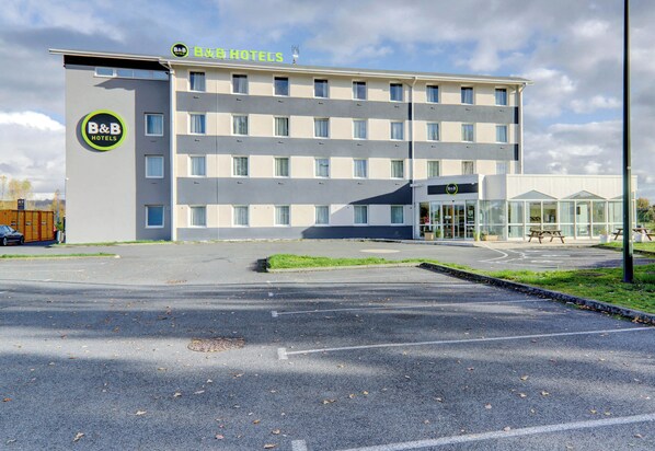 Un hotel tipo casa de huéspedes con un diseño moderno, que cuenta con estacionamiento y entrada de vidrio.