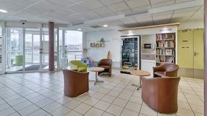 Un espace d’attente moderne équipé d’un distributeur automatique, de sièges et d’une bibliothèque.
