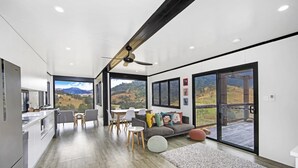 A modern kitchen with a view of the countryside, a dining area with a large window, and a cozy seating area with a view. - Bindera Container House (BINDERA)