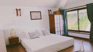 A bedroom with a large bed, a nightstand, a wardrobe, and a window with curtains.