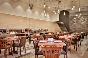 A modern dining area with multiple tables and chairs, a kitchen counter with various food items, and a staircase leading to an upper level. - Ameri Plaza, Tbilisi (Tbilisi)